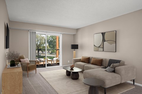 A living room with a grey couch, a wooden side table, and a large window.
