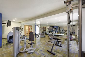 A gym with a variety of equipment including a treadmill, weights, and a television.