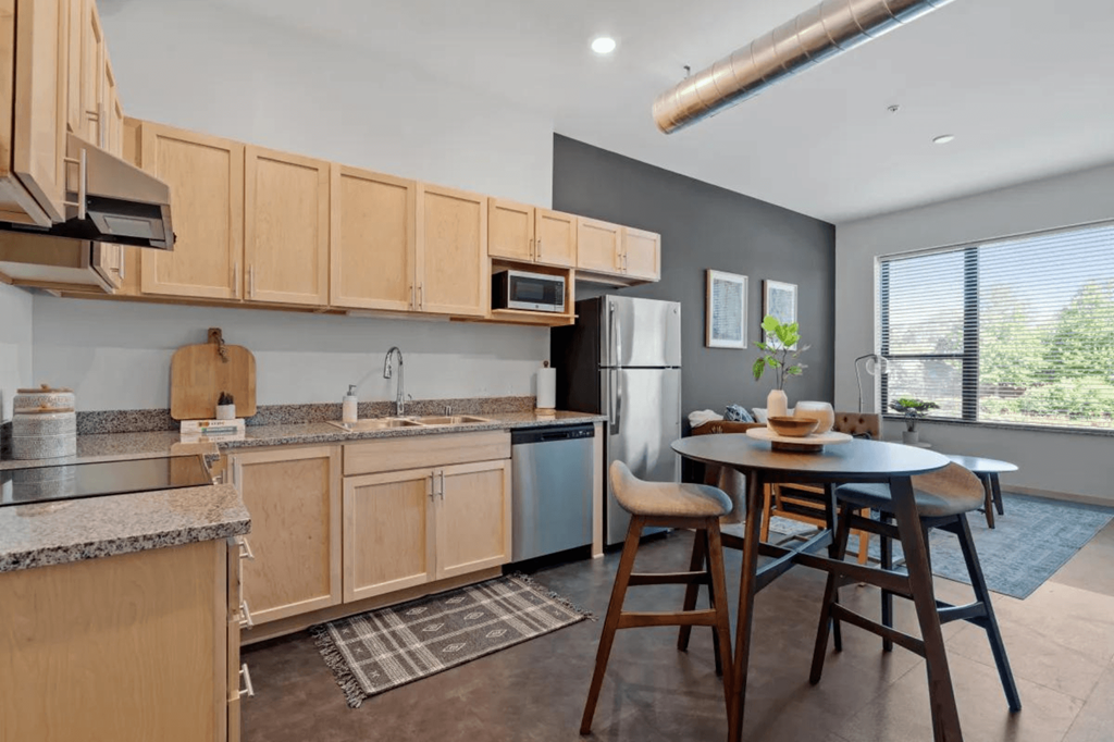 a kitchen with wooden cabinets and a table with chairs at Zelia on Seven, St Louis Park