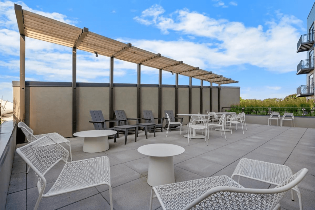 a patio with chairs and tables on the roof of a building at Zelia on Seven, St Louis Park, MN, 55416