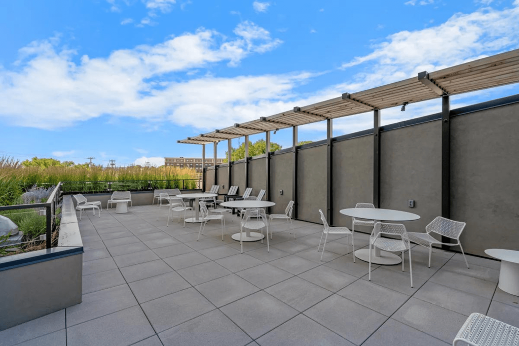 a patio with tables and chairs on the roof of a building at Zelia on Seven, St Louis Park, 55416