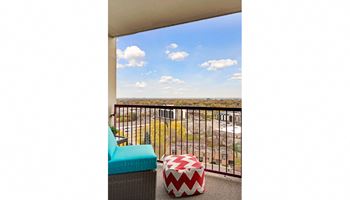 A balcony with a blue chair and a red and white ottoman.