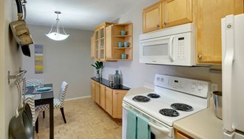 A kitchen with a white stove and a white microwave.
