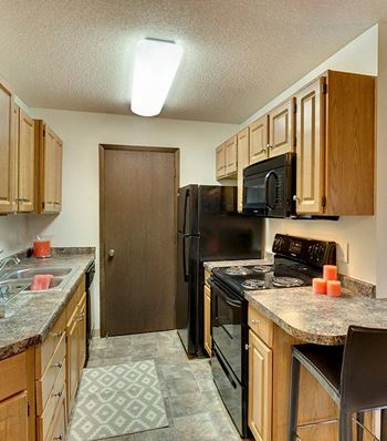 A kitchen with a black refrigerator and a black stove top oven.