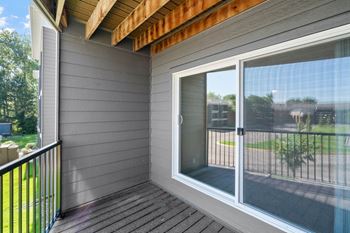 A balcony with a glass door and a black railing.