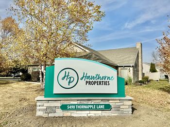 A sign for Hawthorne Properties stands in front of a house.