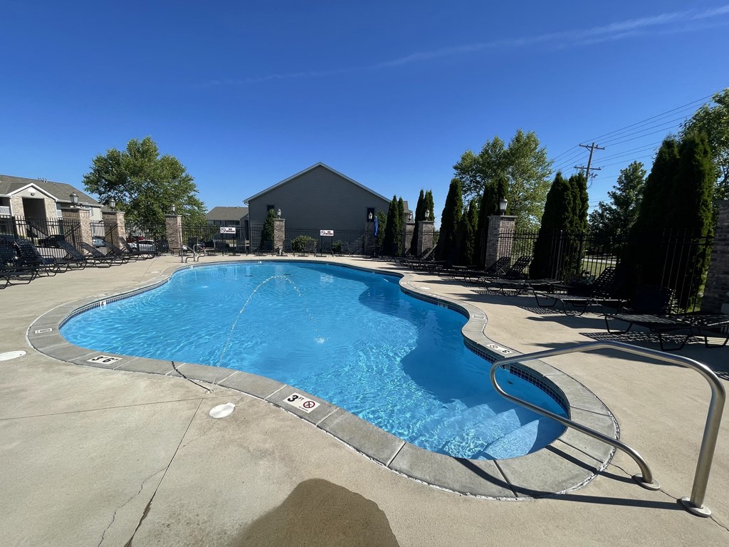 a resort style pool with chairs around it and a building in the background at Hawthorne Properties in Lafayette, IN 47905
