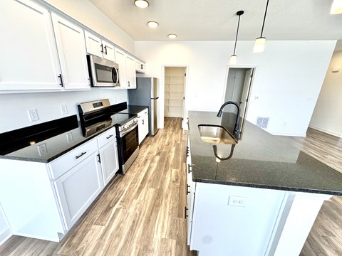 A kitchen with white cabinets and black countertops.