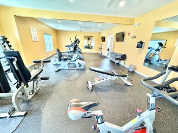 A gym with a variety of equipment including treadmills, stationary bikes, and weight machines.