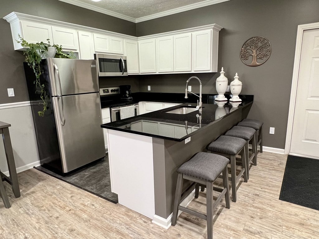 A kitchen with a black counter top and white cabinets.