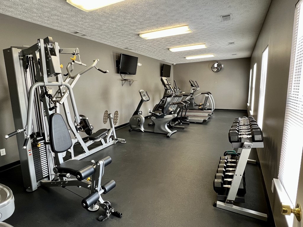 A gym with a variety of equipment including weights and cardio machines.
