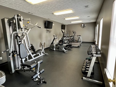 A gym with a variety of equipment including weights and cardio machines.