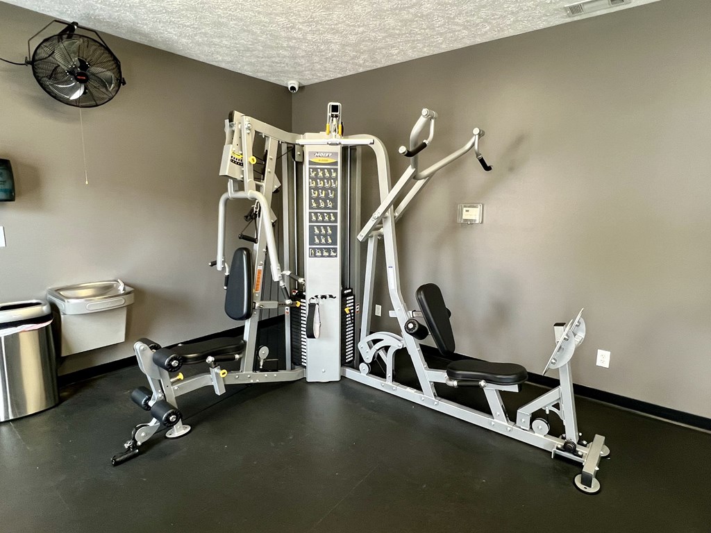 A home gym with a weight machine, a bench, and a fan.