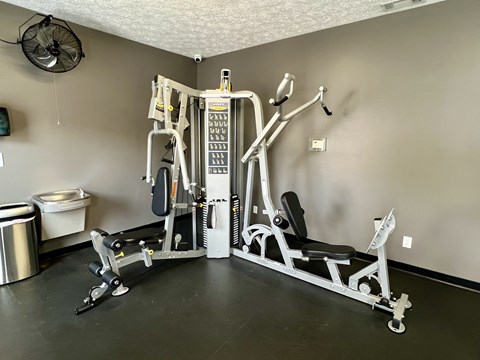 A home gym with a weight machine, a bench, and a fan.
