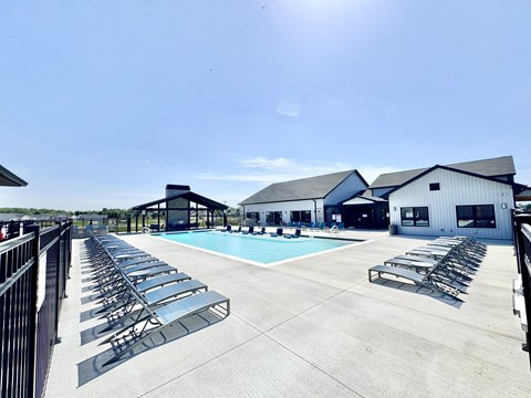 A sunny day at the pool with lounge chairs and a clear blue sky.