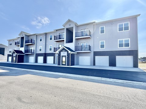A modern apartment building with multiple balconies and garage doors.