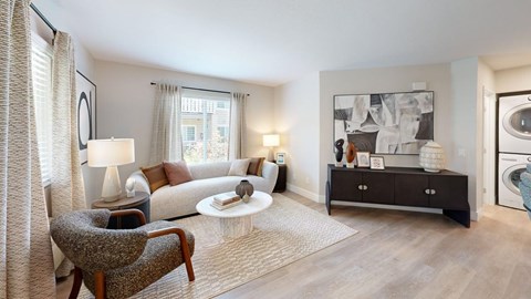 A well-lit, modern living room with a grey armchair, a white coffee table, and a large artwork on the wall.