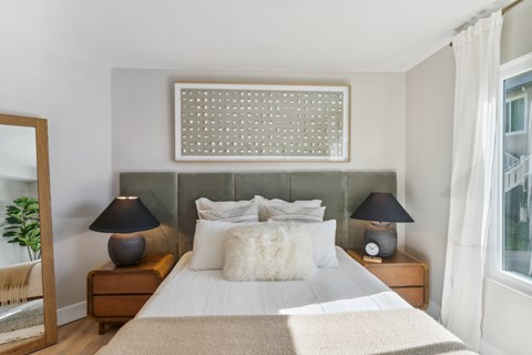 A bedroom with a large bed and two lamps on either side of the bed.