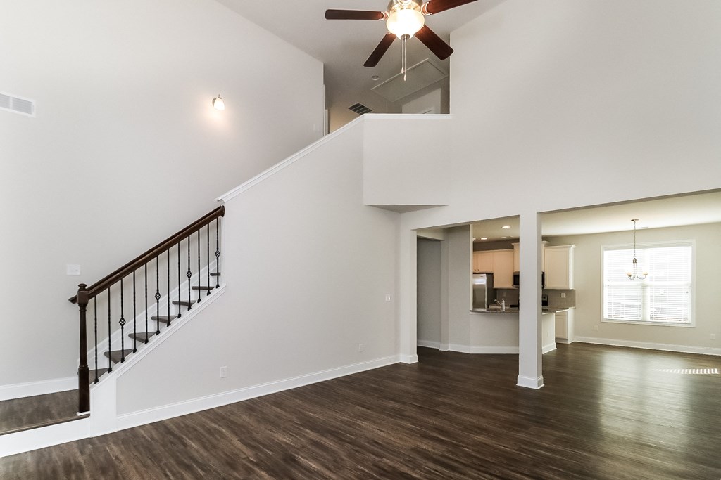 an empty living room with a staircase and a ceiling fan