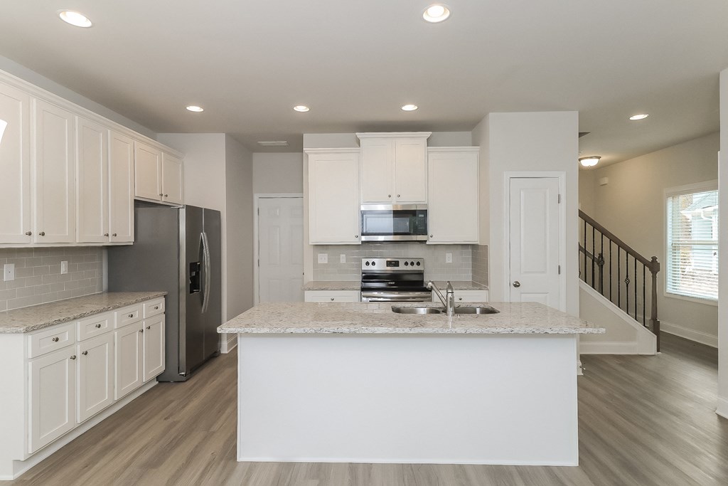 a kitchen with white cabinets and a marble counter top