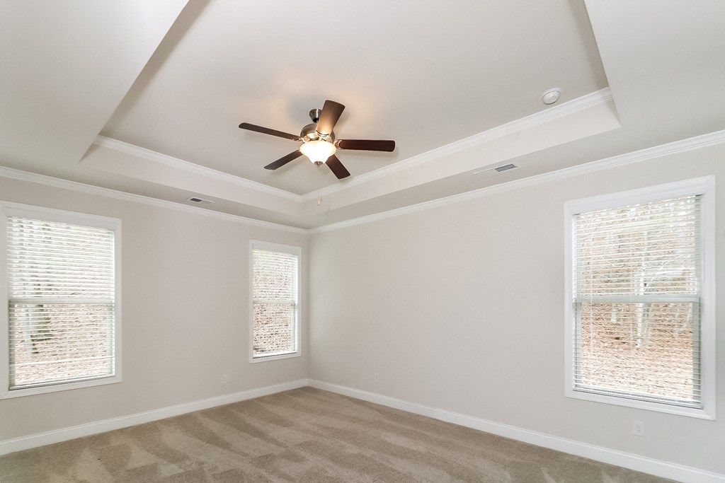 an empty living room with a ceiling fan and two windows