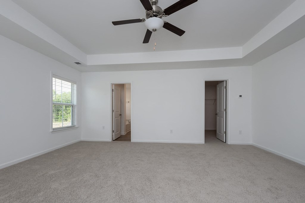 a living room with white walls and a ceiling fan