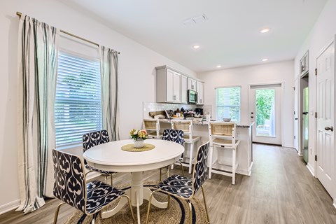 A dining room with a white table and chairs.