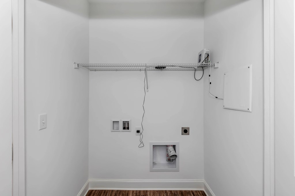 A white room with a shelf and electrical outlets.