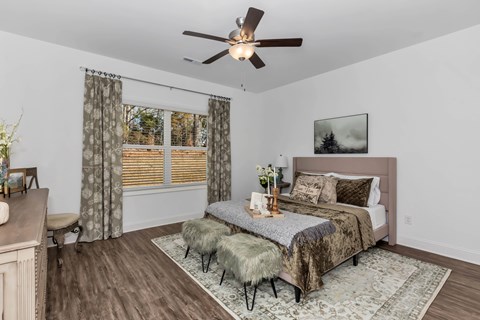 A bedroom with a bed, a bench, and a ceiling fan.