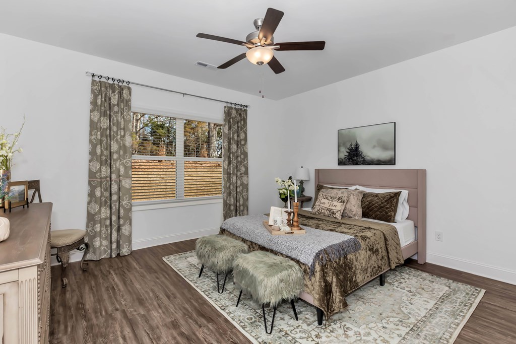 A bedroom with a bed, a bench, and a ceiling fan.