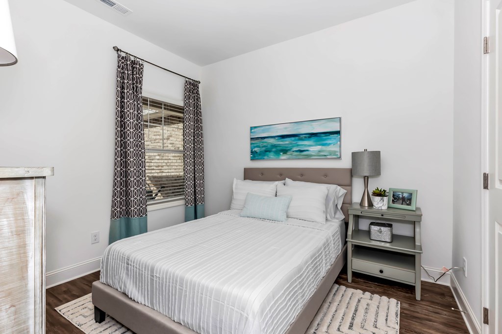 A bedroom with a bed, nightstand, and a painting on the wall.