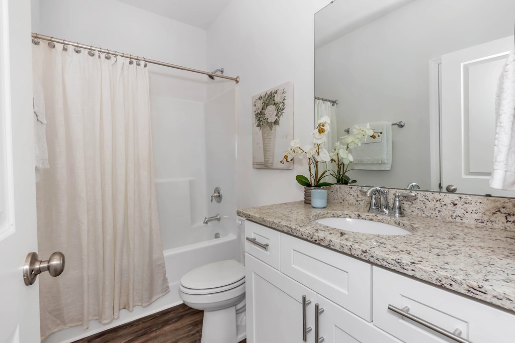 A white bathroom with a toilet, sink, and shower.