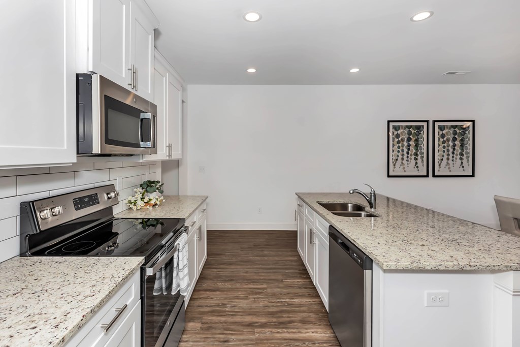 A kitchen with white cabinets and granite countertops.