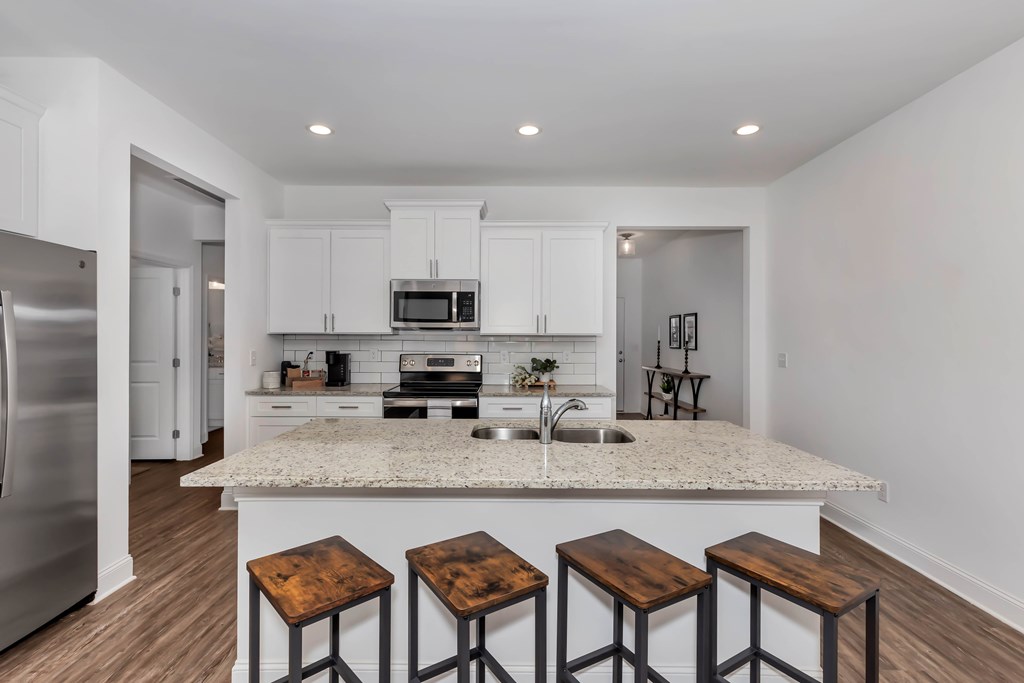 A kitchen with white cabinets and a granite countertop.