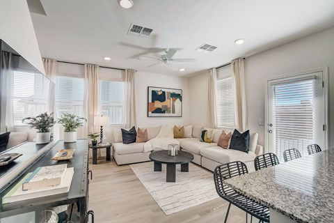 A modern living room with a white couch and a painting on the wall.