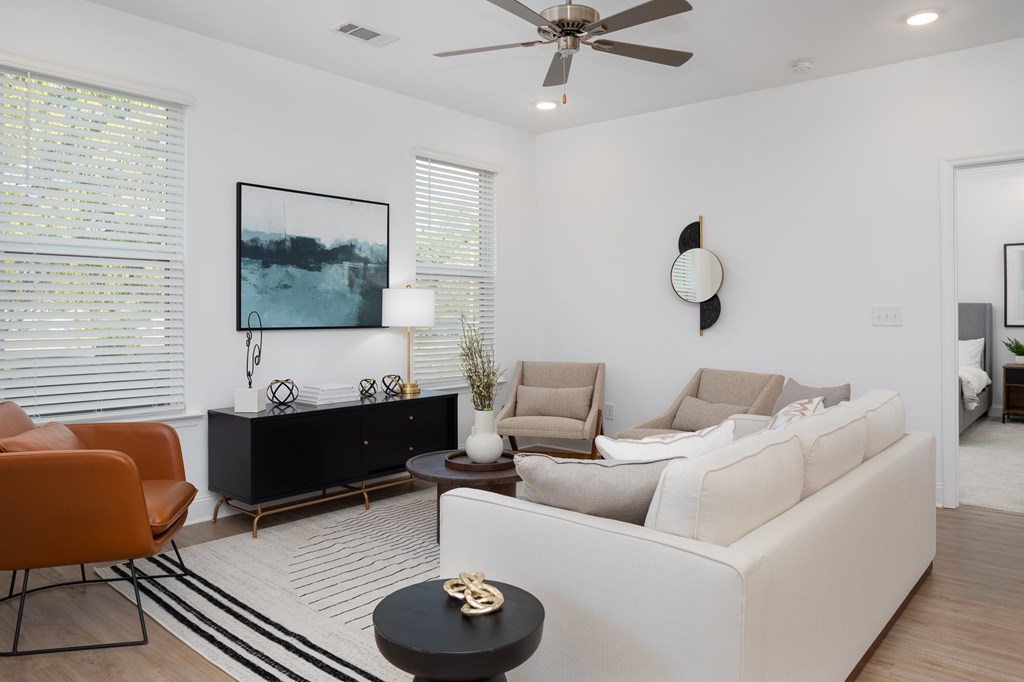 A living room with a white couch, orange chairs, and a black coffee table.