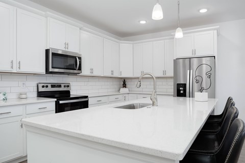 A modern kitchen with white cabinets and a white countertop.