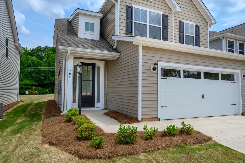 a tan house with a white garage door and a lawn