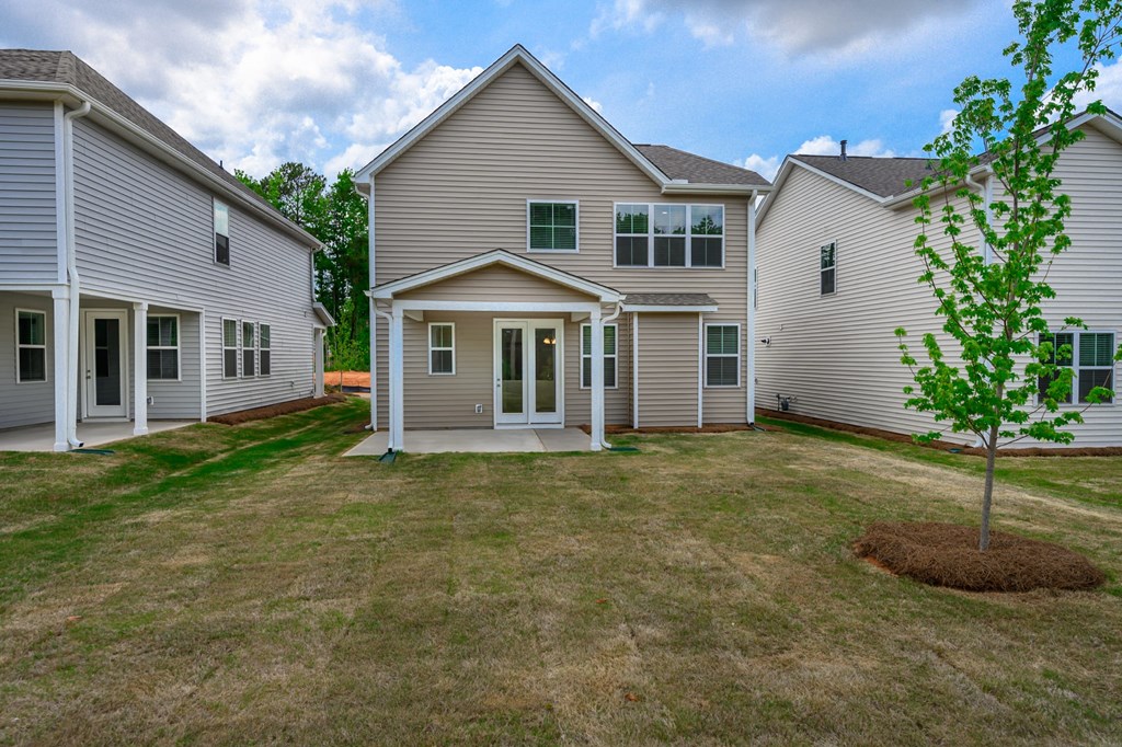 the backyard of a house with a small tree in the yard