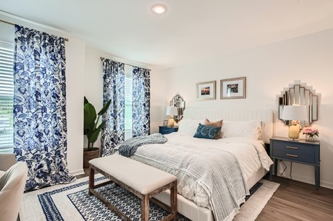 A bedroom with a bed, nightstand, and a mirror on the wall.