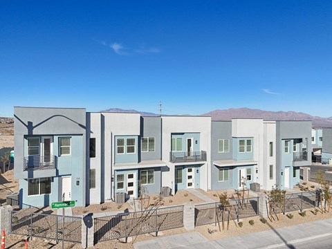 A row of modern houses with blue and grey exteriors are shown in a residential area.
