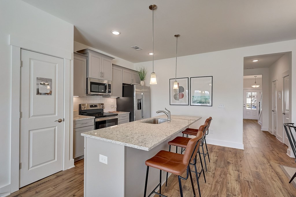 A kitchen with a white island and brown bar stools.