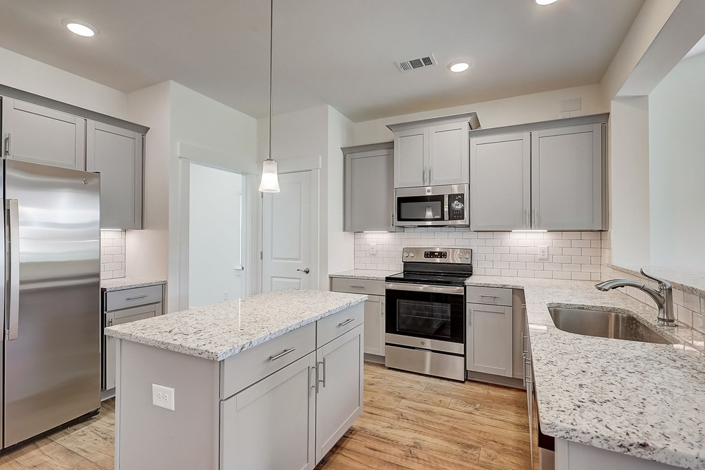 A modern kitchen with a granite countertop and stainless steel appliances.