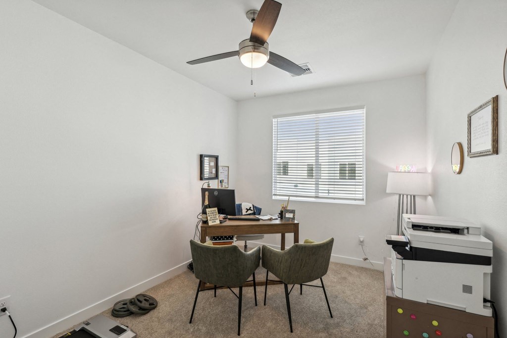 A room with a desk, chairs, and a printer.