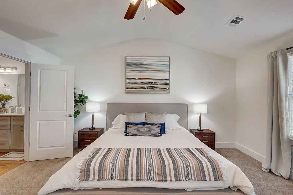 A bedroom with a large bed and a ceiling fan.