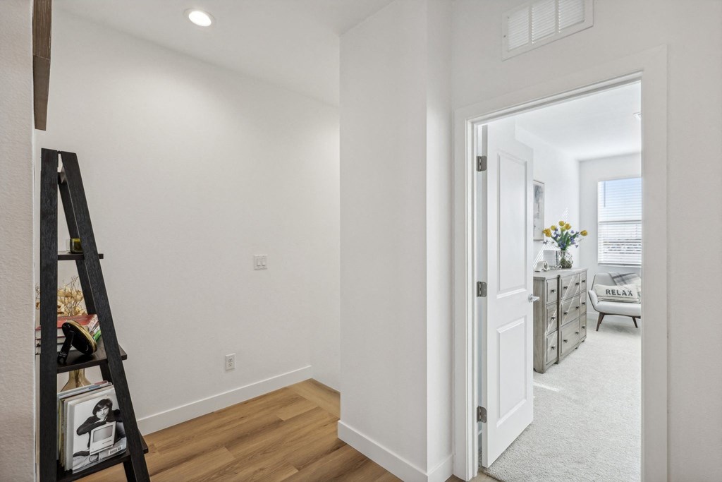 A white hallway with a doorway leading to a living room.