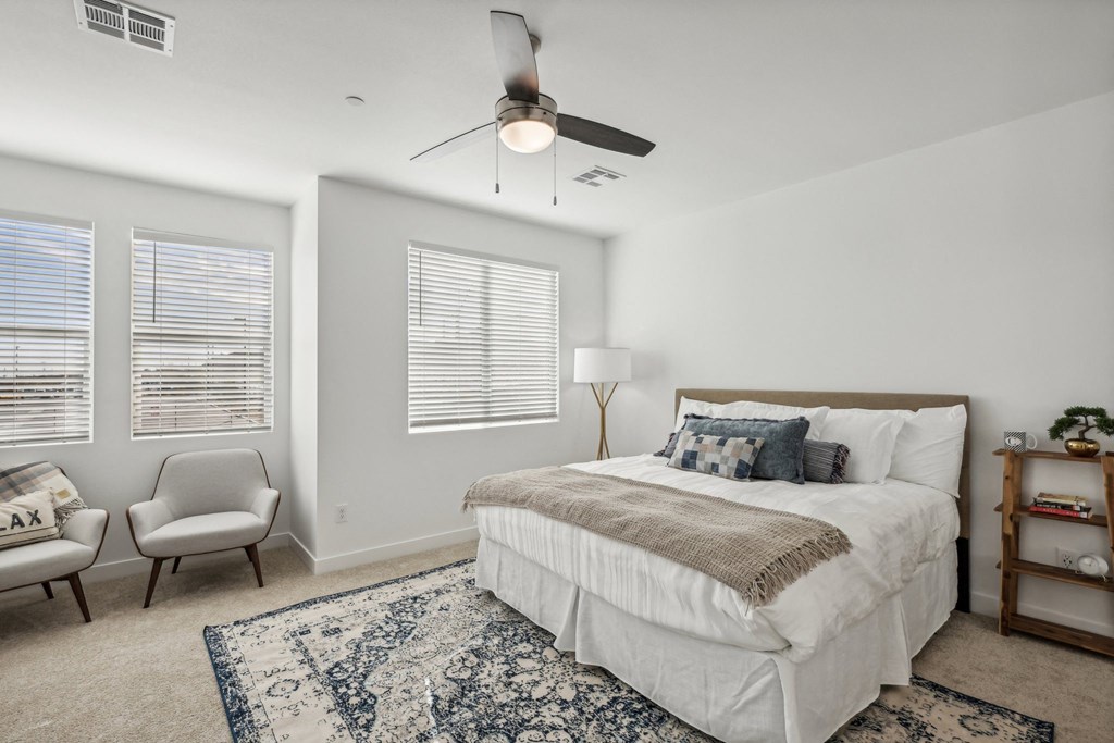 A bedroom with a large bed, a chair, and a ceiling fan.