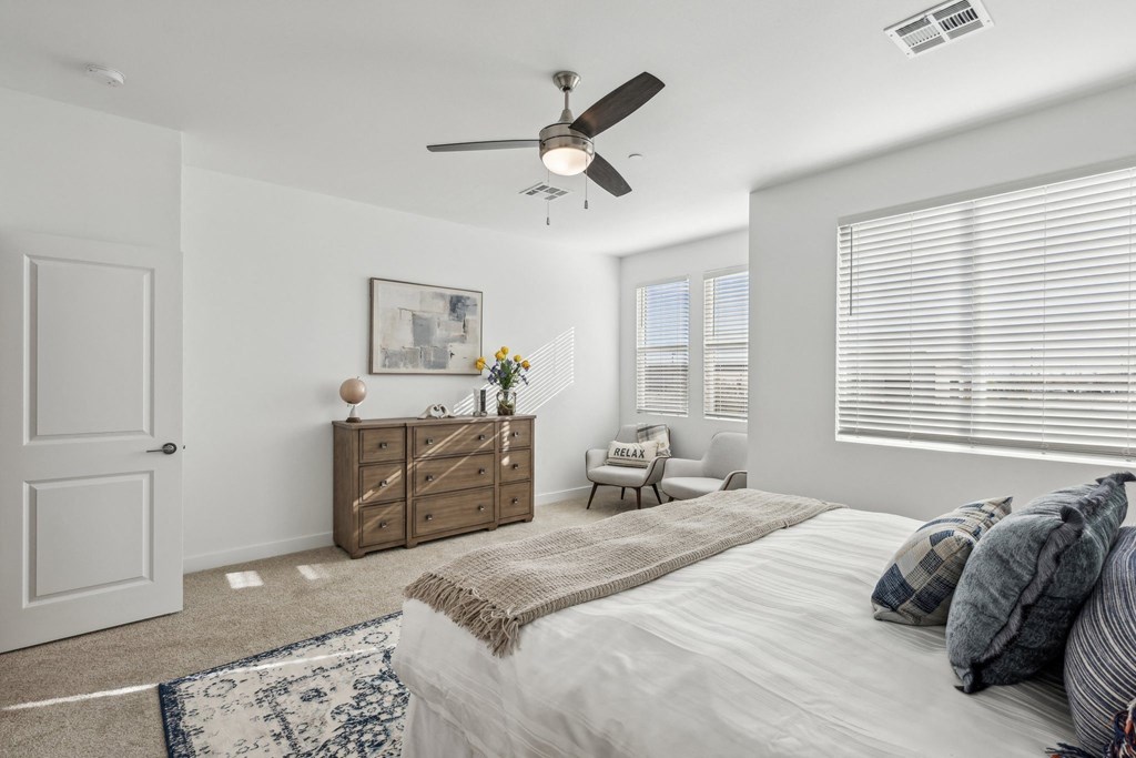 A bedroom with a bed, dresser, and window with blinds.