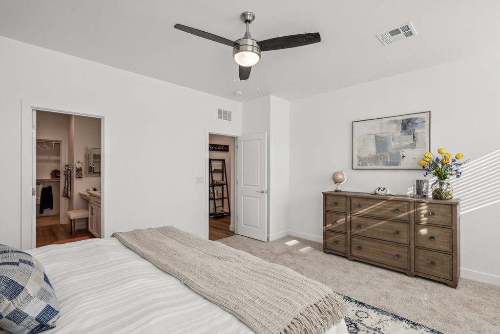 A bedroom with a bed, dresser, and a ceiling fan.