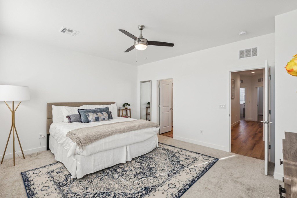A bedroom with a large bed and a ceiling fan.